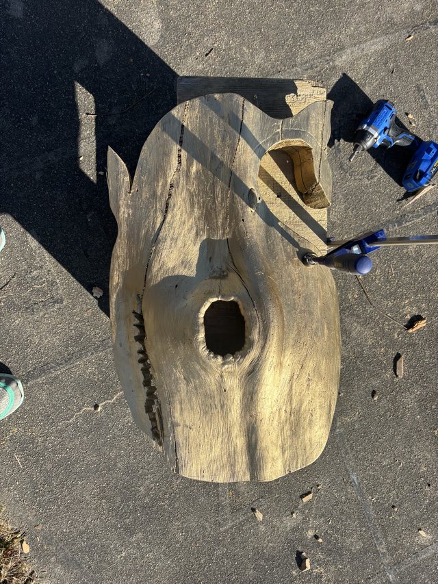 Carved wooden face sculpture with an open mouth and angular features